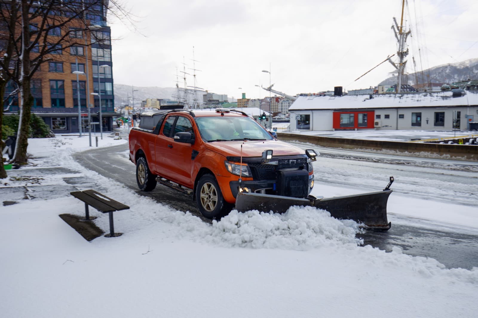 Pickup truck with a snow plow clearing a snowy street